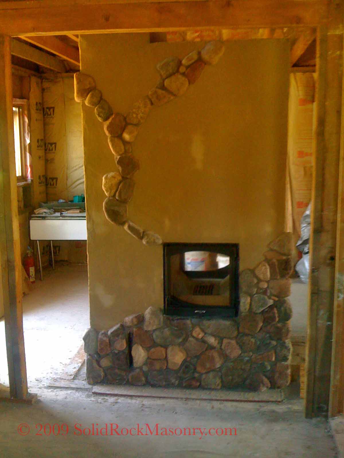 Naylor SR-13 Finnish Contraflow Masonry Heater & SR-18 Russian Bell heater. Finished with 4″ CMU and clay plaster and whimsical thin fieldstone veneer